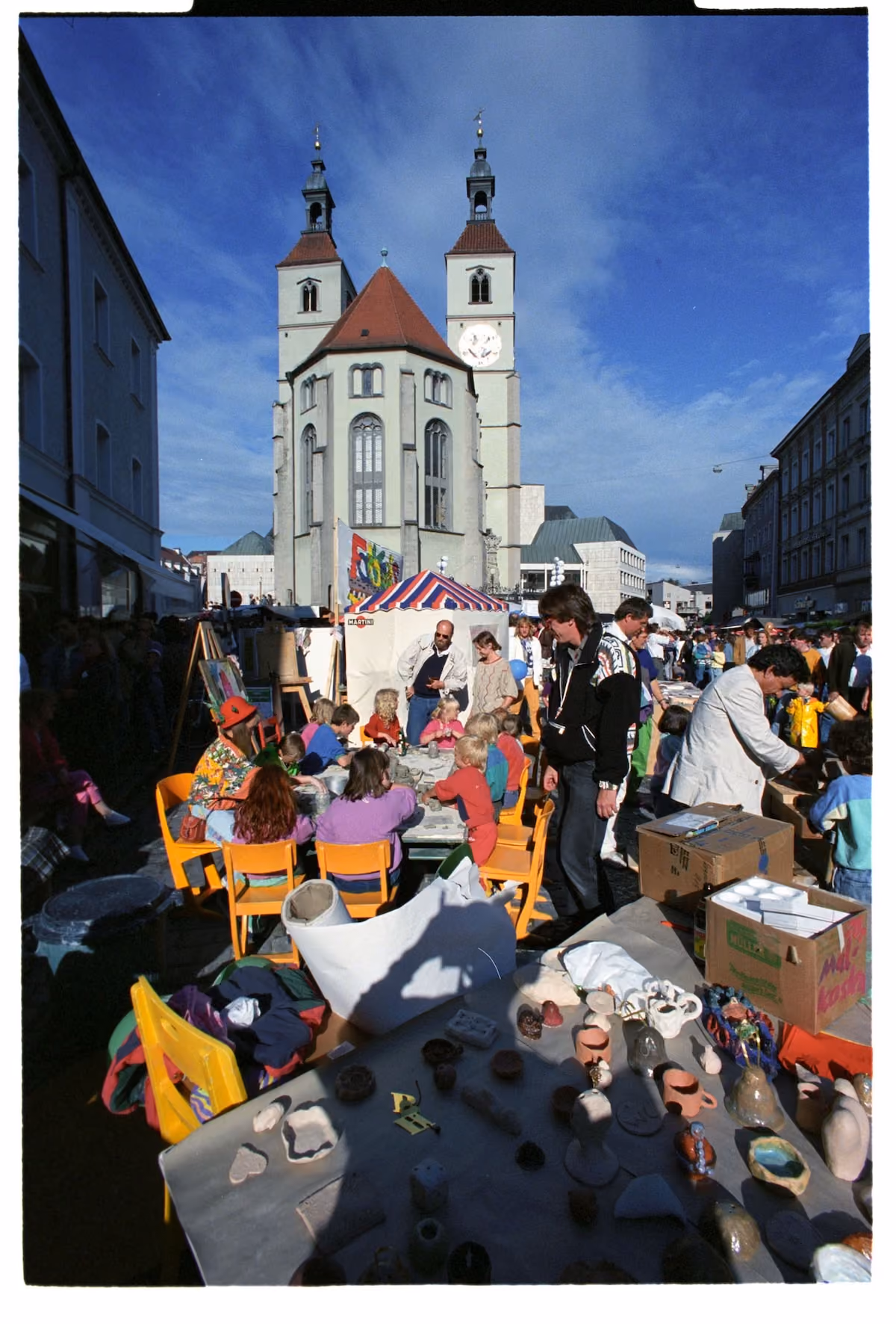 Kinder gestalten Keramik an einem Bürgerfeststand vor der Regensburger Altstadtkulisse 1990.