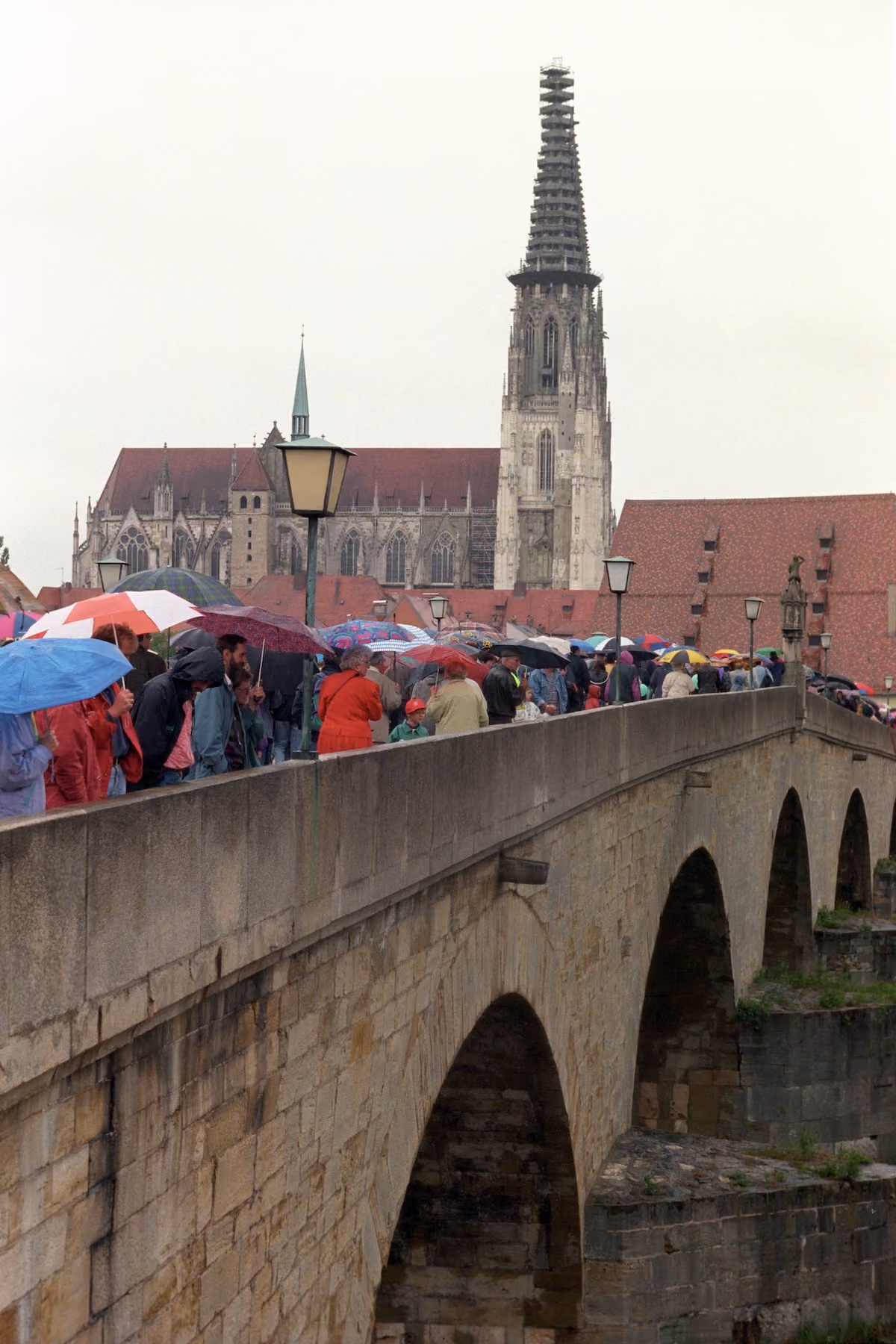 Besucherinnen und Besucher mit Regenschirmen auf der Steinernen Brücke beim Bürgerfest 1997.