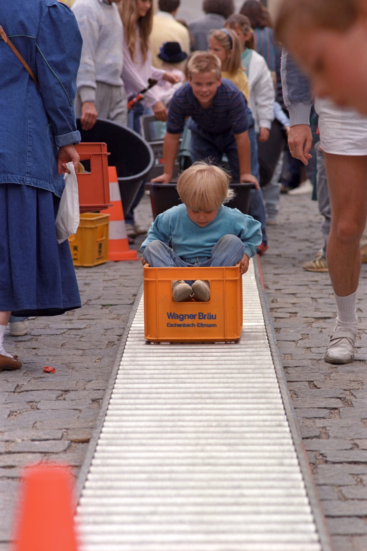 Kinder fahren in Getränkekisten über eine Rollenbahn beim Regensburger Bürgerfest 1988.
