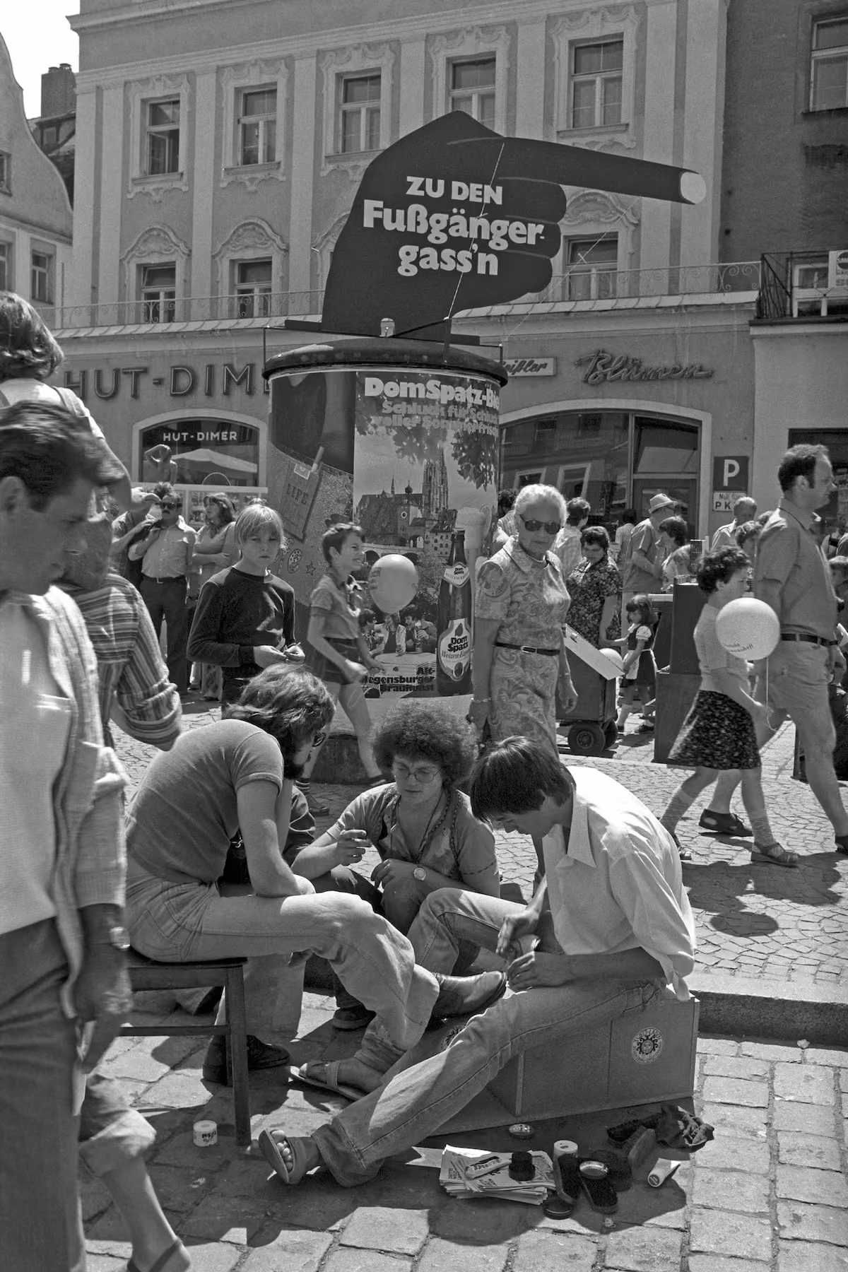 Straßenszene mit Schuhputzern und dem Schild „Zu den Fußgängergass’n“ beim Regensburger Bürgerfest 1977.