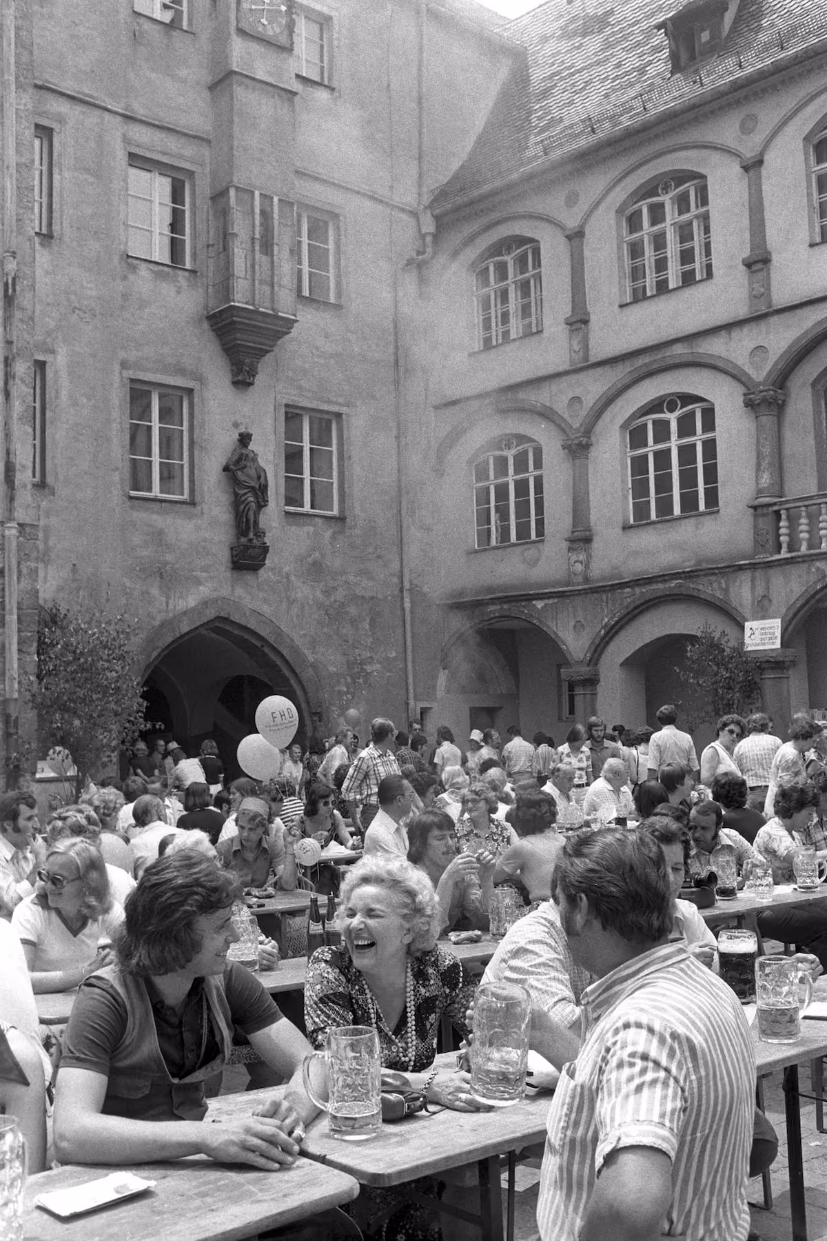 Fröhliche Festgäste an Biertischen in einem historischen Regensburger Innenhof beim Bürgerfest 1975.