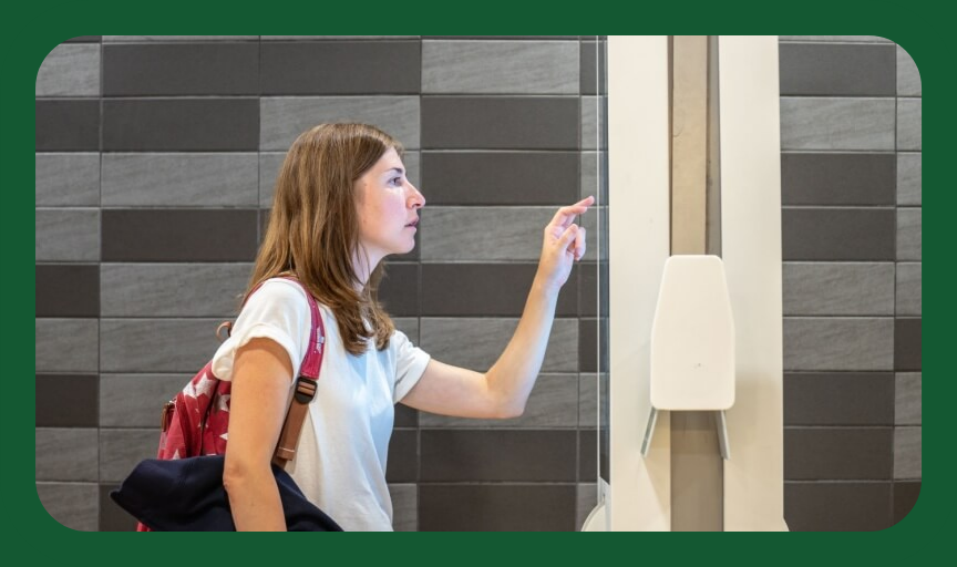 A customer concentrates as they use a large touchscreen display to make a purchase in-store, to illustrate the concept of customer efforts score