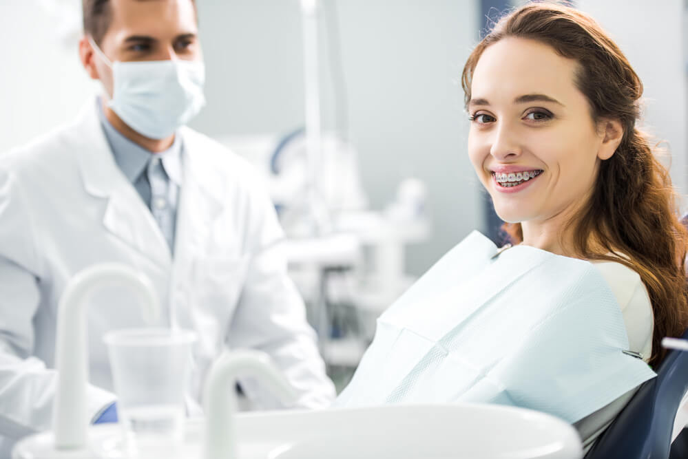 a patient with braces smiles during her appointment with an orthodontist in 33062