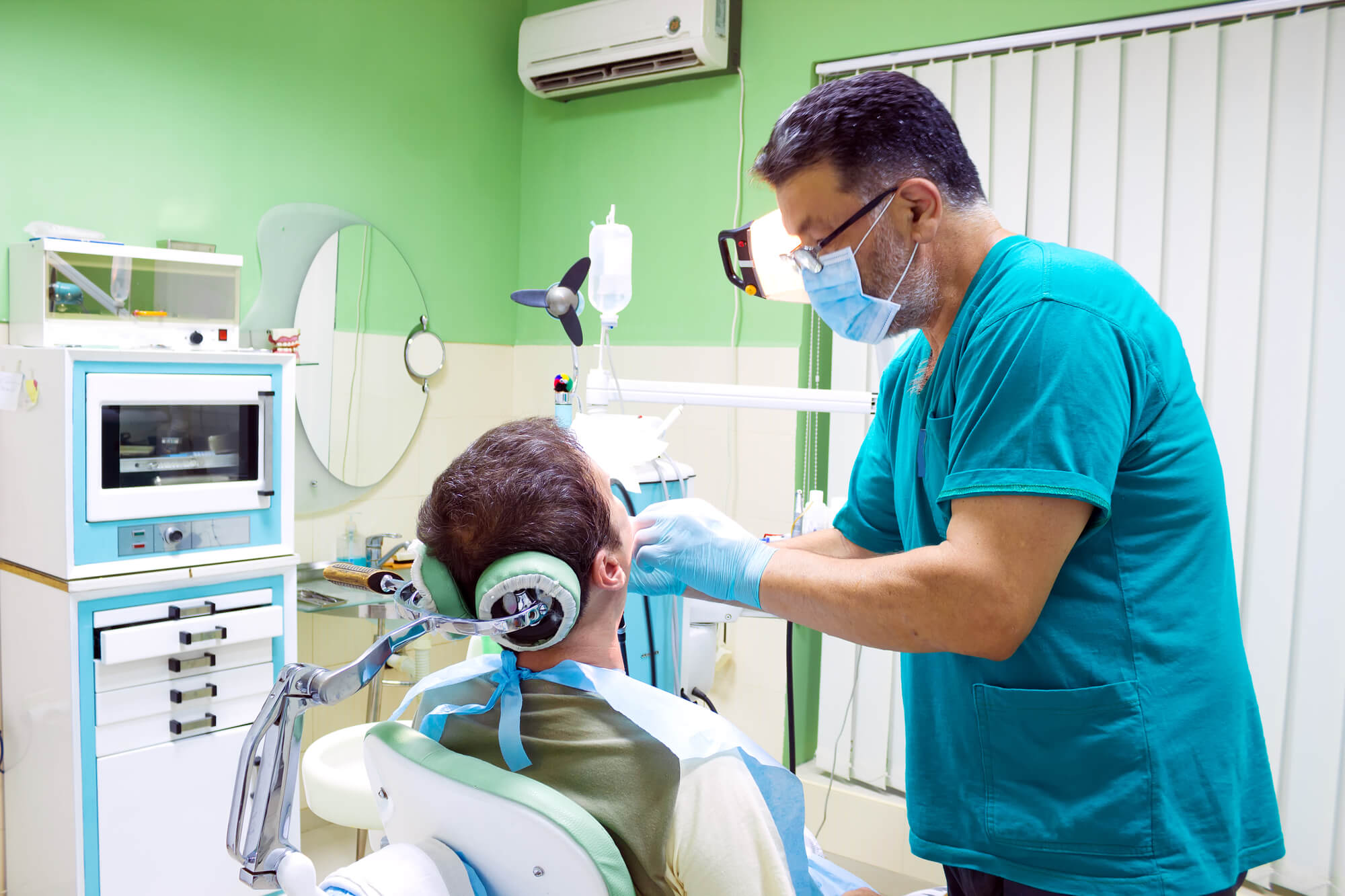 dentist examines patient's teeth before getting dental implants in 33062