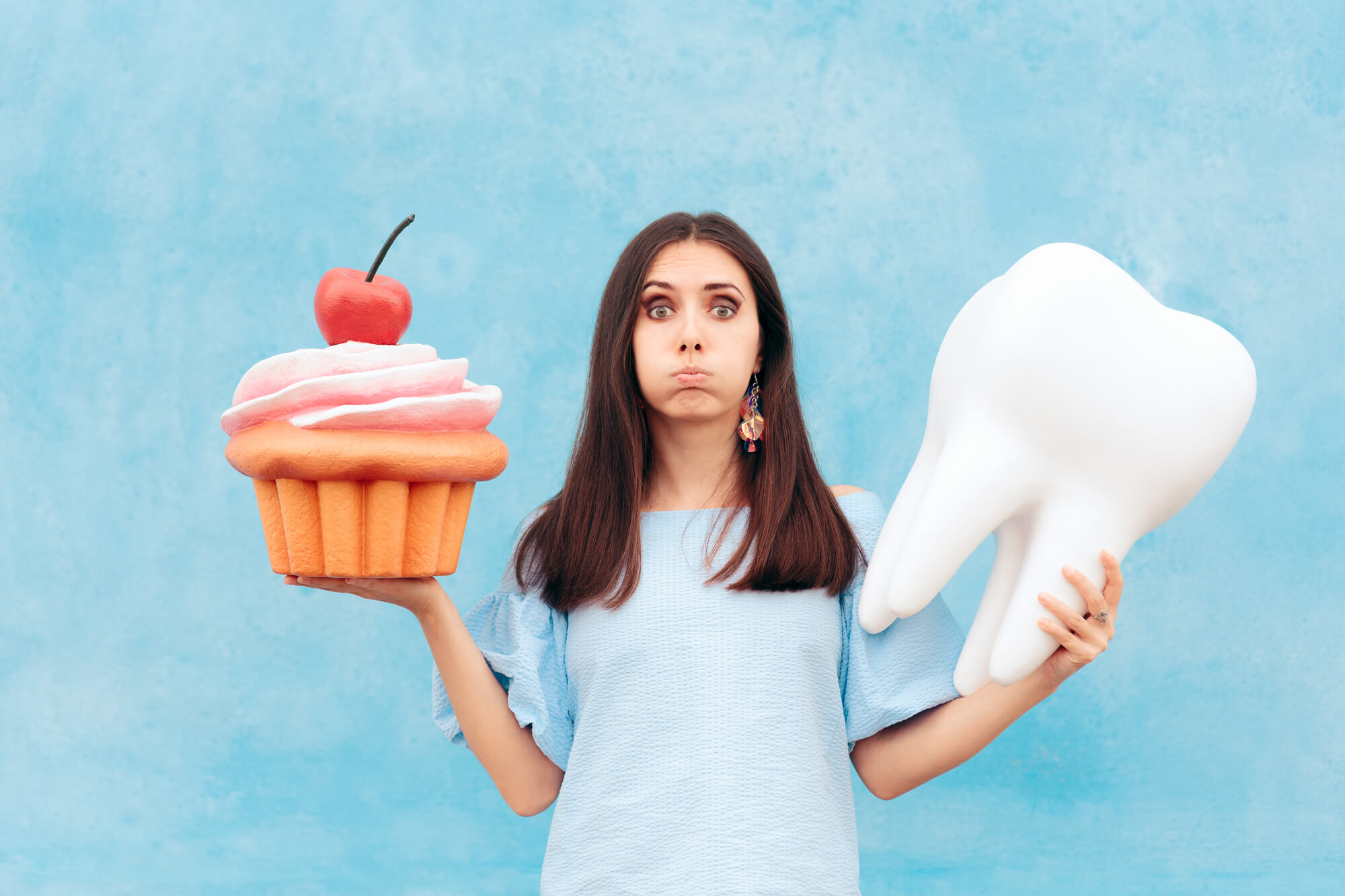Woman Holding Cupcake and Tooth as Requested by a Cosmetic Dentist Pompano Beach