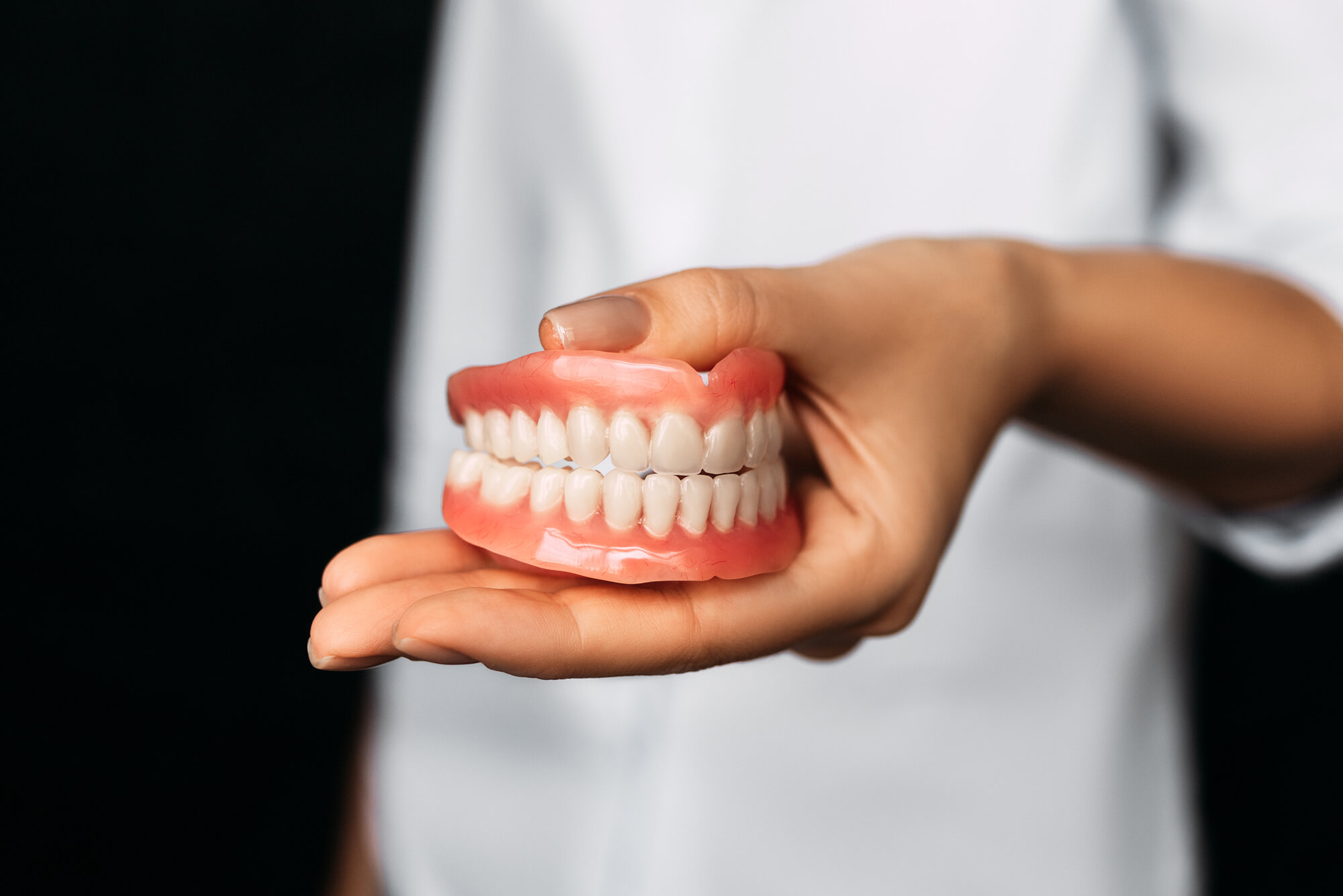 dentist holds Dentures in Pompano Beach in one hand