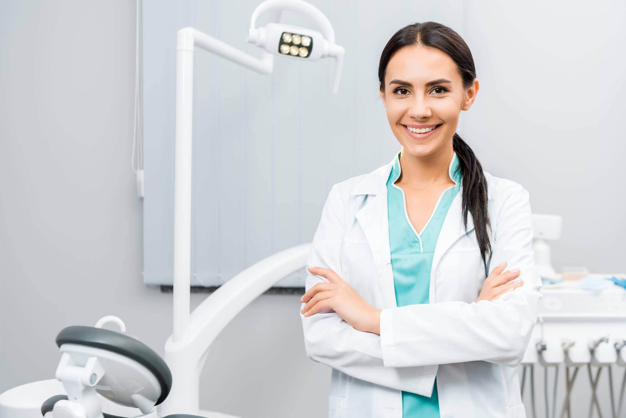 A Dentist in Pompano Beach smiling at her dental treatment room