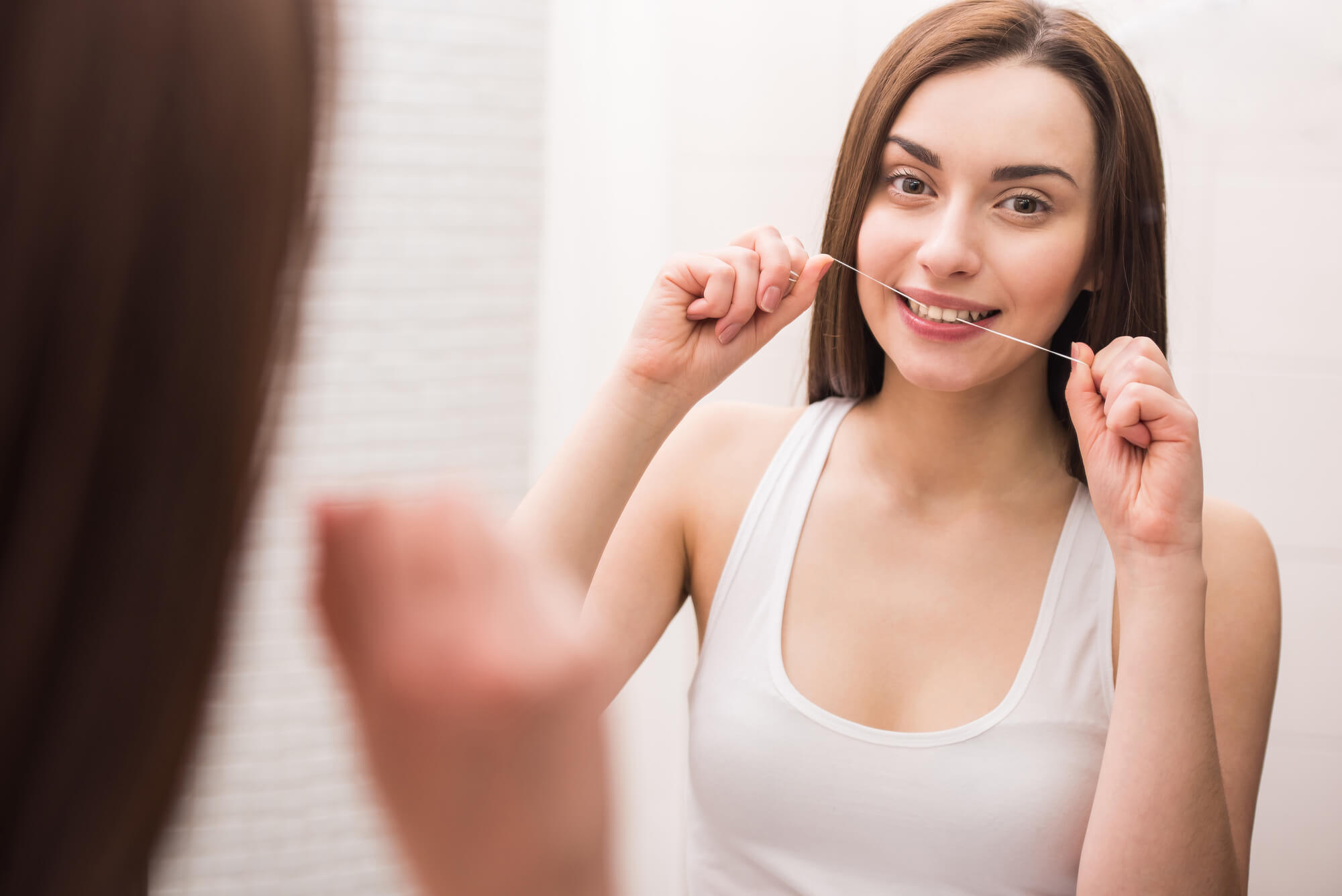woman flossing her teeth as per instruction by her Dentist 33062