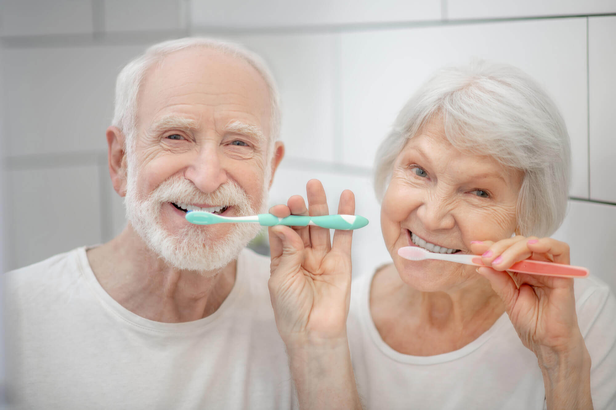 A senior couple takes care of their  Dental Implants in 33062 by brushing their teeth
