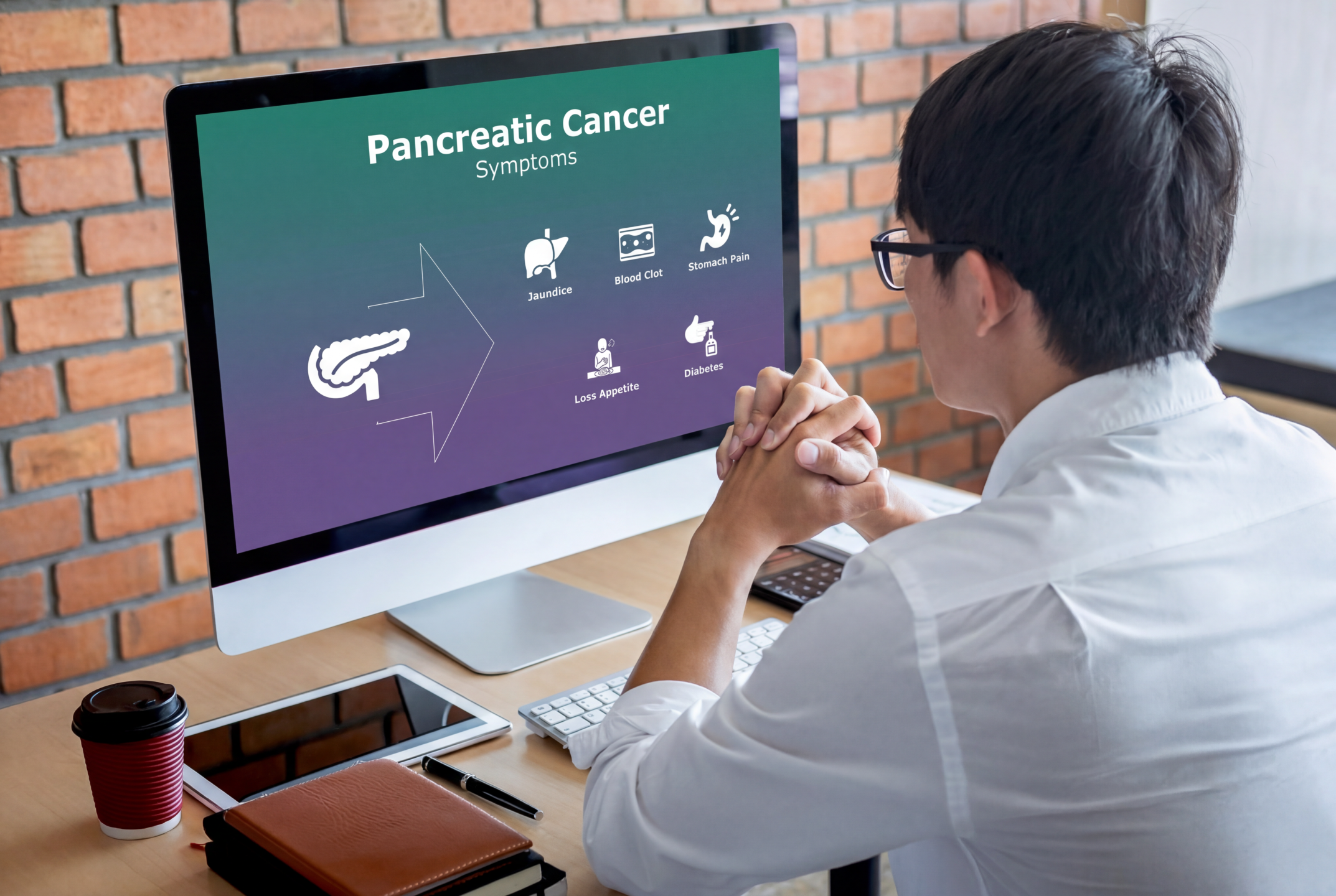 Healthcare learner reviewing pancreatic cancer symptoms using an editable Pancreatic Cancer PowerPoint Template on a desktop computer.