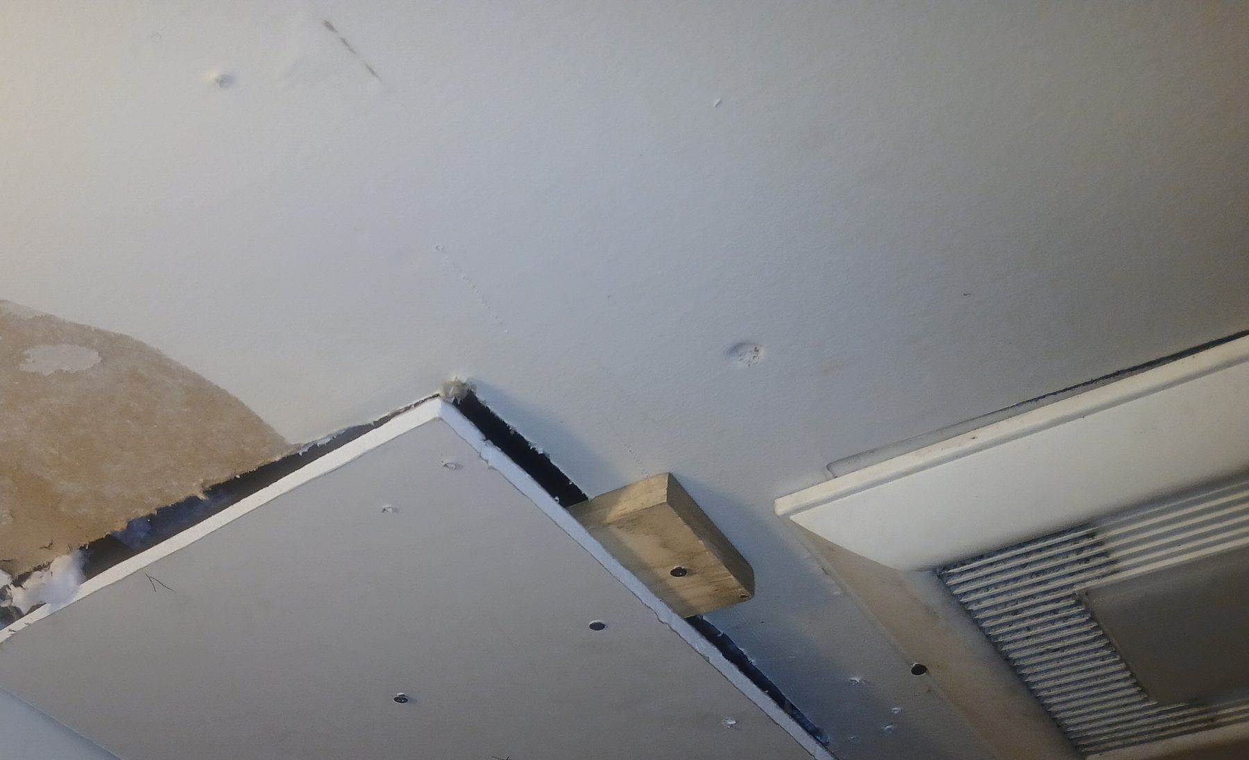 Ceiling access hatch with moisture damage to surrounding drywall