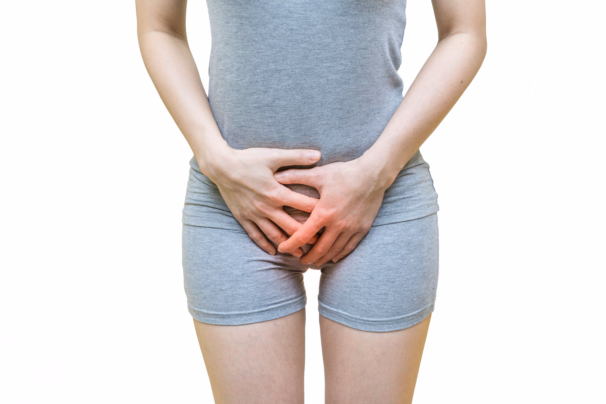 Woman holding her lower abdomen, illustrating symptoms that may be associated with pelvic floor dysfunction