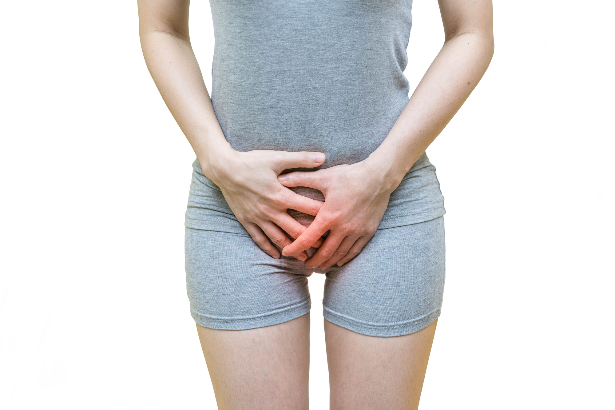 Woman holding her lower abdomen, illustrating symptoms that may be associated with pelvic floor dysfunction