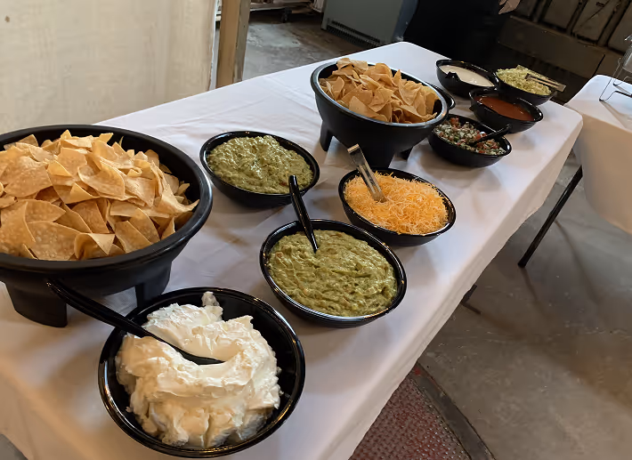 Corporate catering chips and dips station with guacamole, sour cream, queso, and fresh salsa