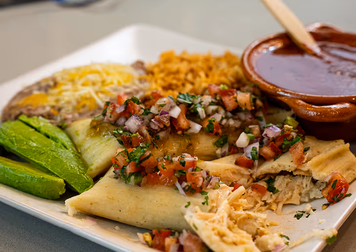 Corporate catering plate of chicken tamales served with rice, beans, and pico de gallo.