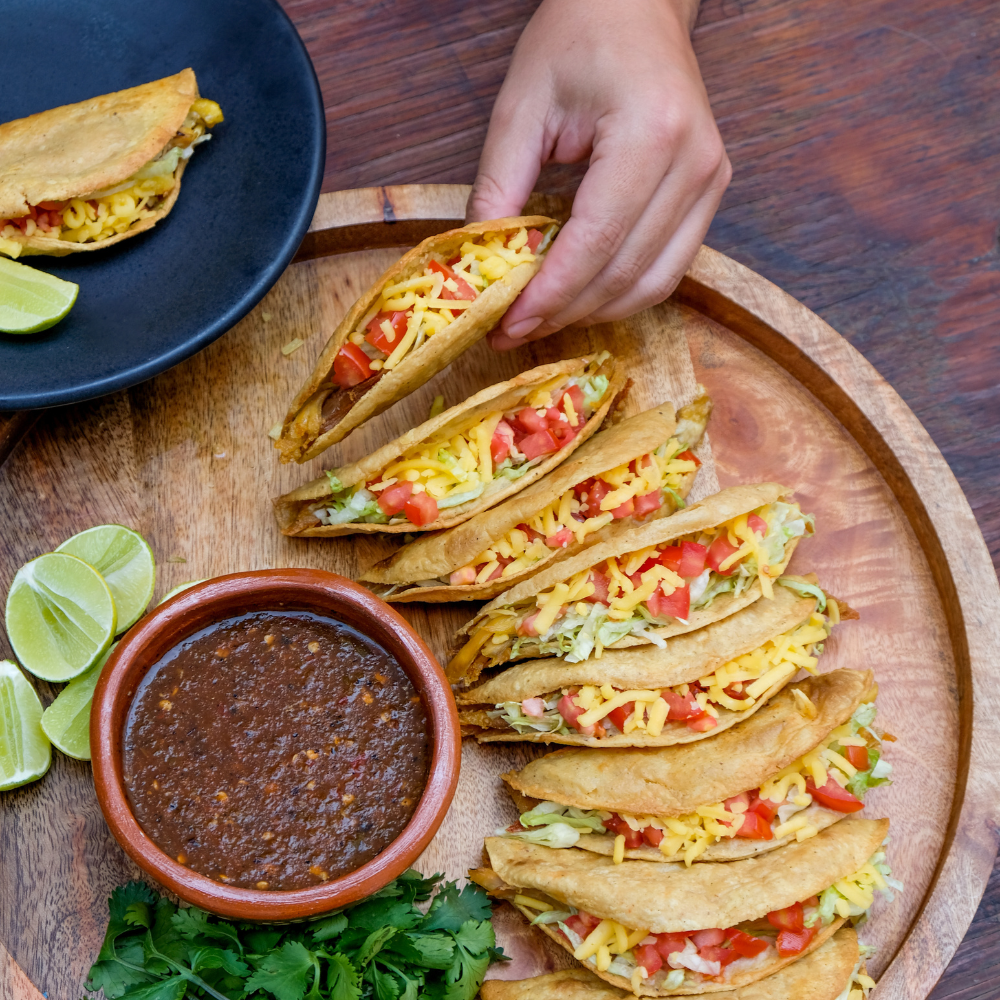 Crispy tacos with cheese and salsa served for corporate catering event.
