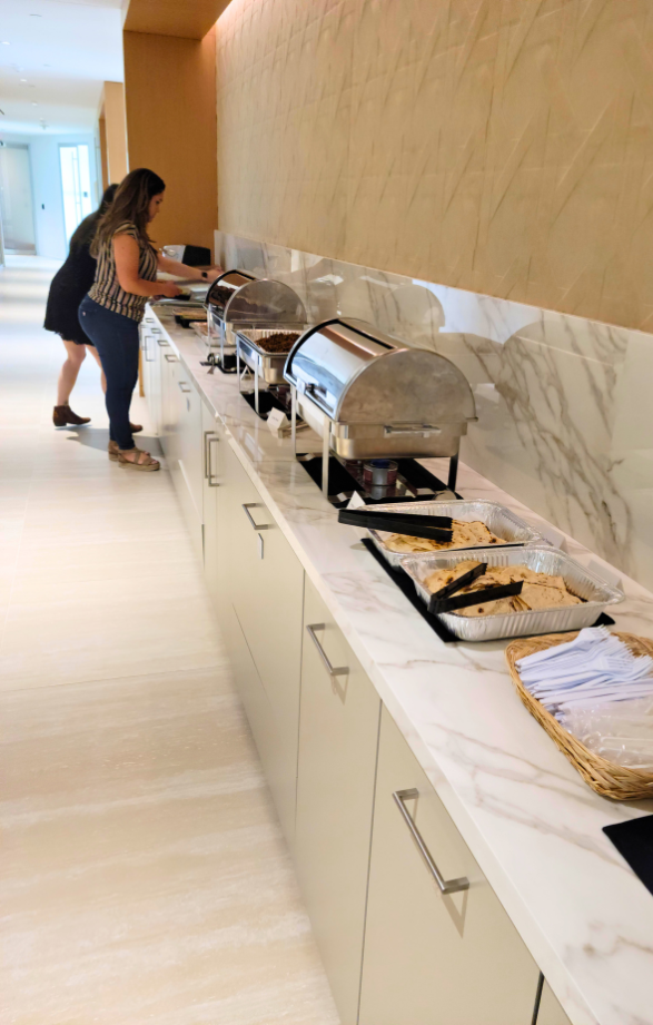 Corporate catering buffet with chafing dishes and tortillas inside a modern office kitchen.