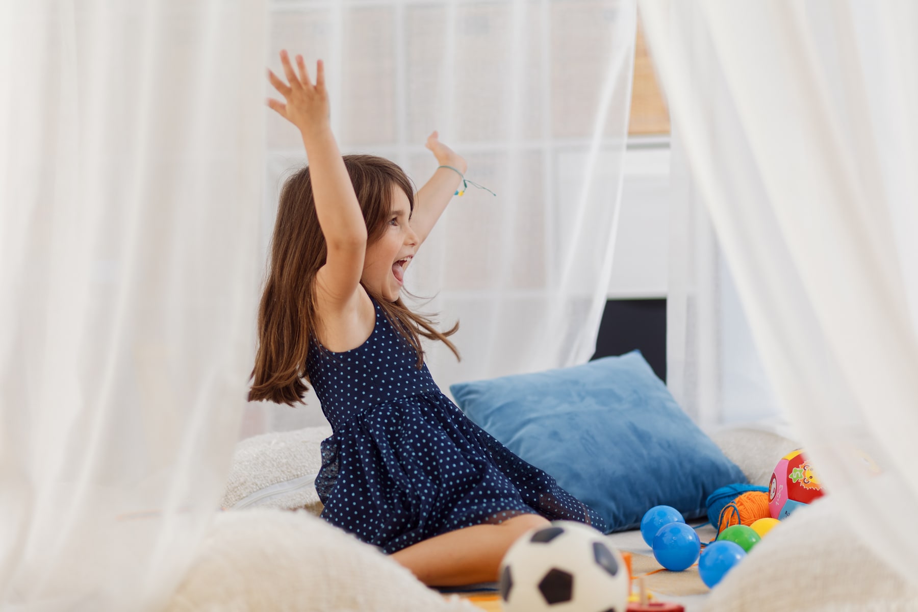 A girl playing among cushions and toys at Dukley Kids Club