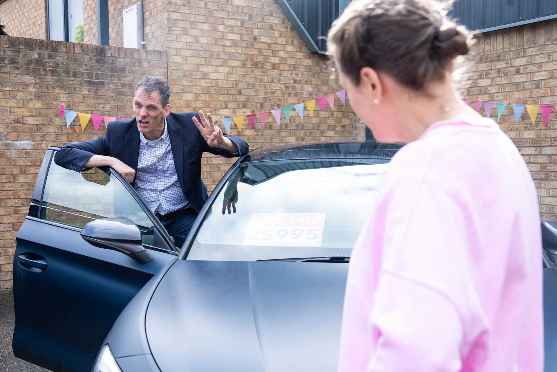 Woman sitting on a red chair looking at her phone in a veterinary clinic waiting area with a receptionist working behind the counter.