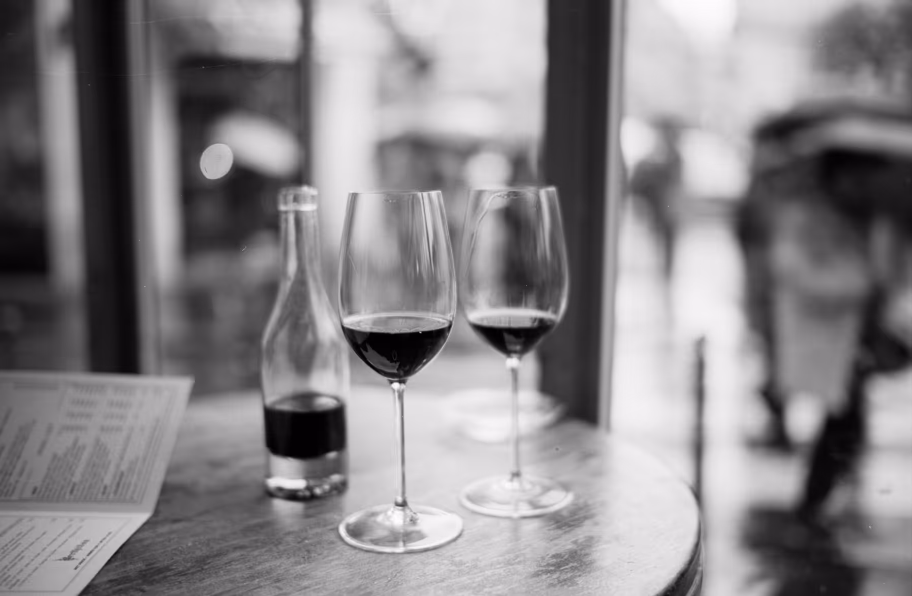 Two wineglasses in front of a wine bottle in a small winebar.