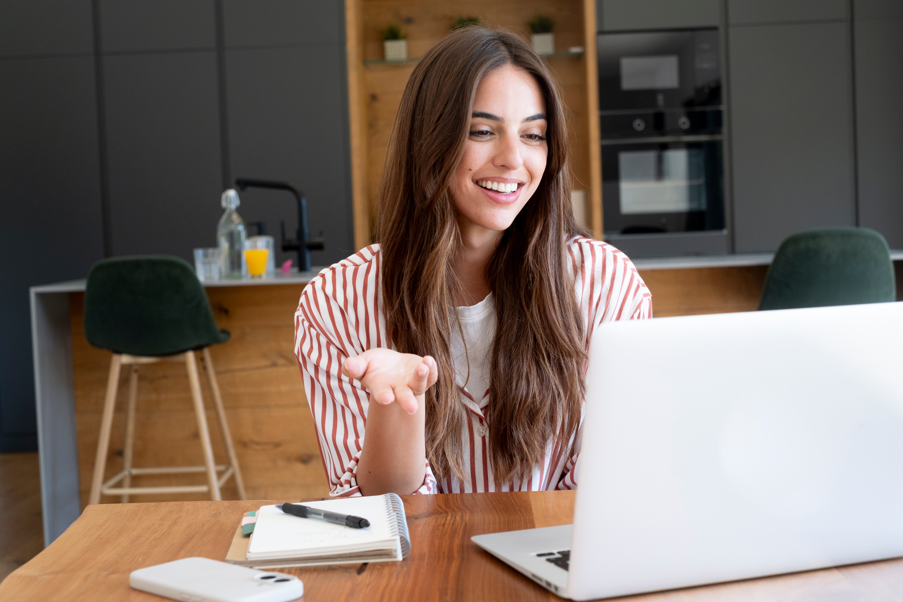 Young woman on laptop at dining room table 