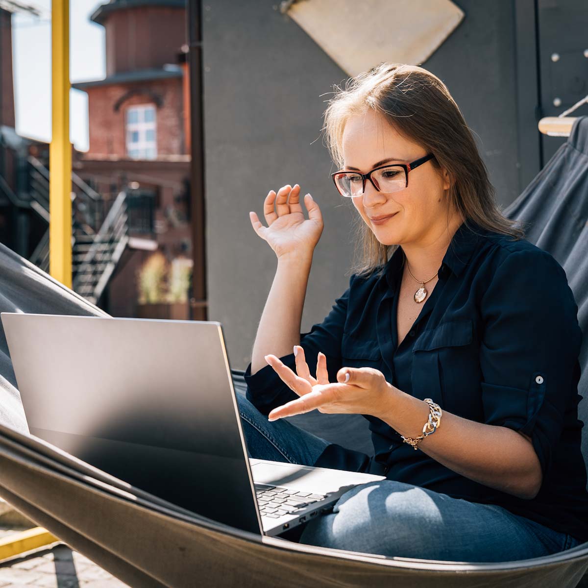 Middle age woman on laptop while sitting in hammock
