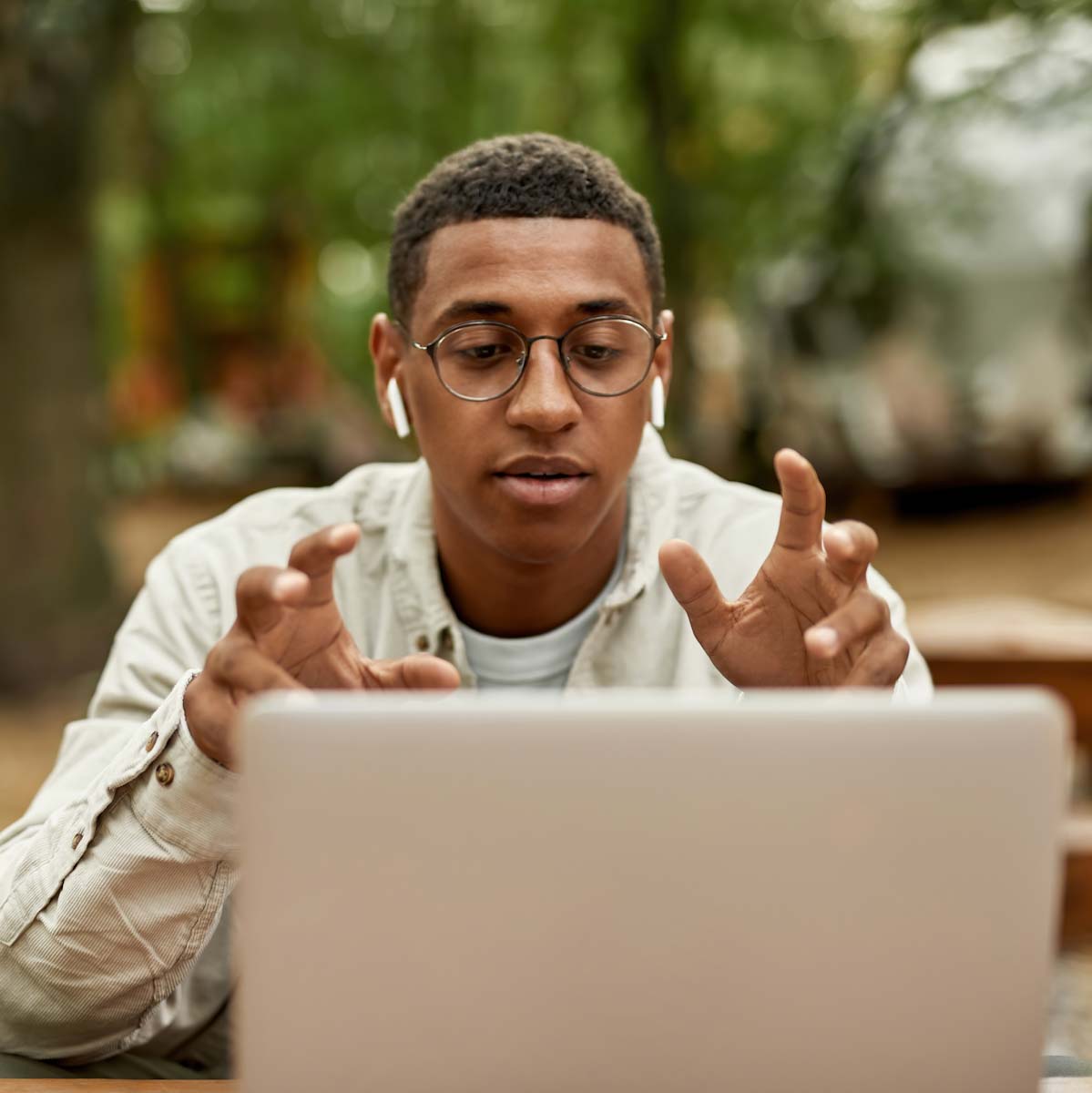 Young man on laptop outside with headphones