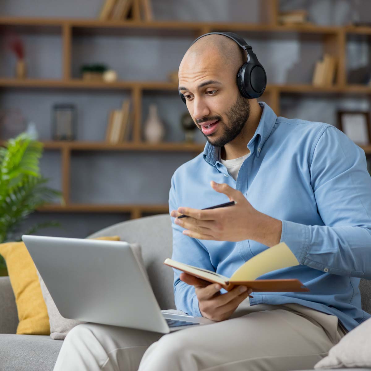 Middle age man on laptop while sitting on couch with headphones on