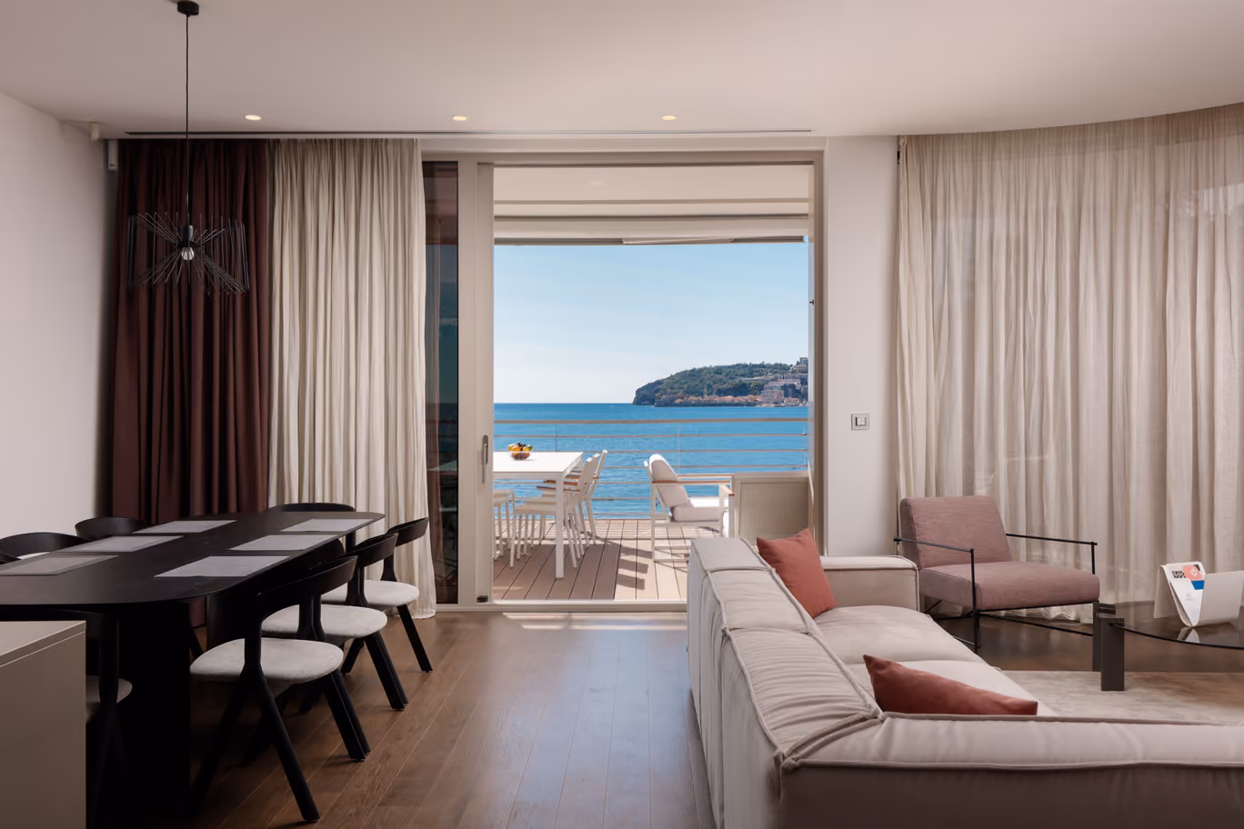 Interior of living room in three-bedroom apartment with comfortable furniture, luxury amenities and panoramic views of Adriatic sea.