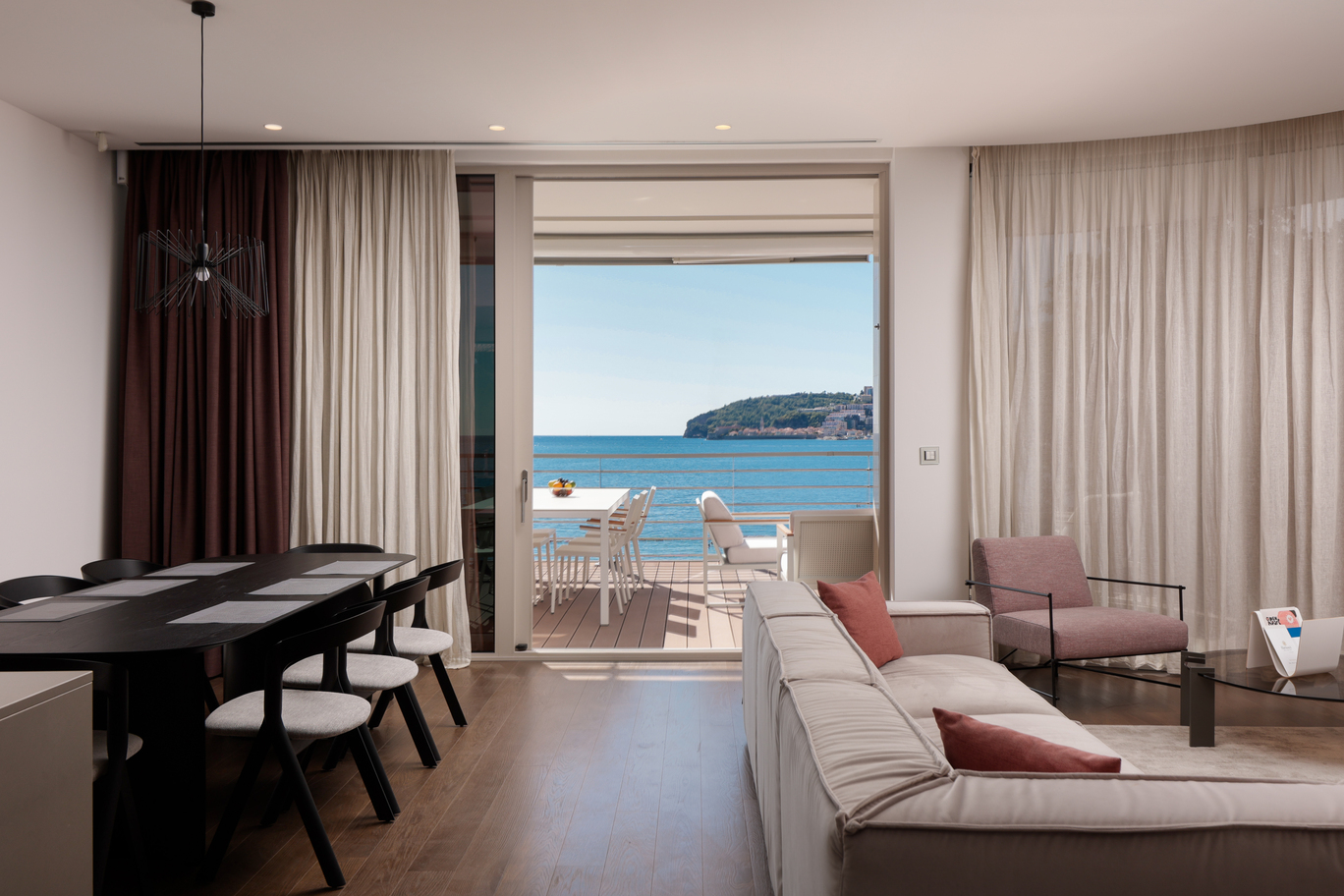 Interior of living room in three-bedroom apartment with comfortable furniture, luxury amenities and panoramic views of Adriatic sea.