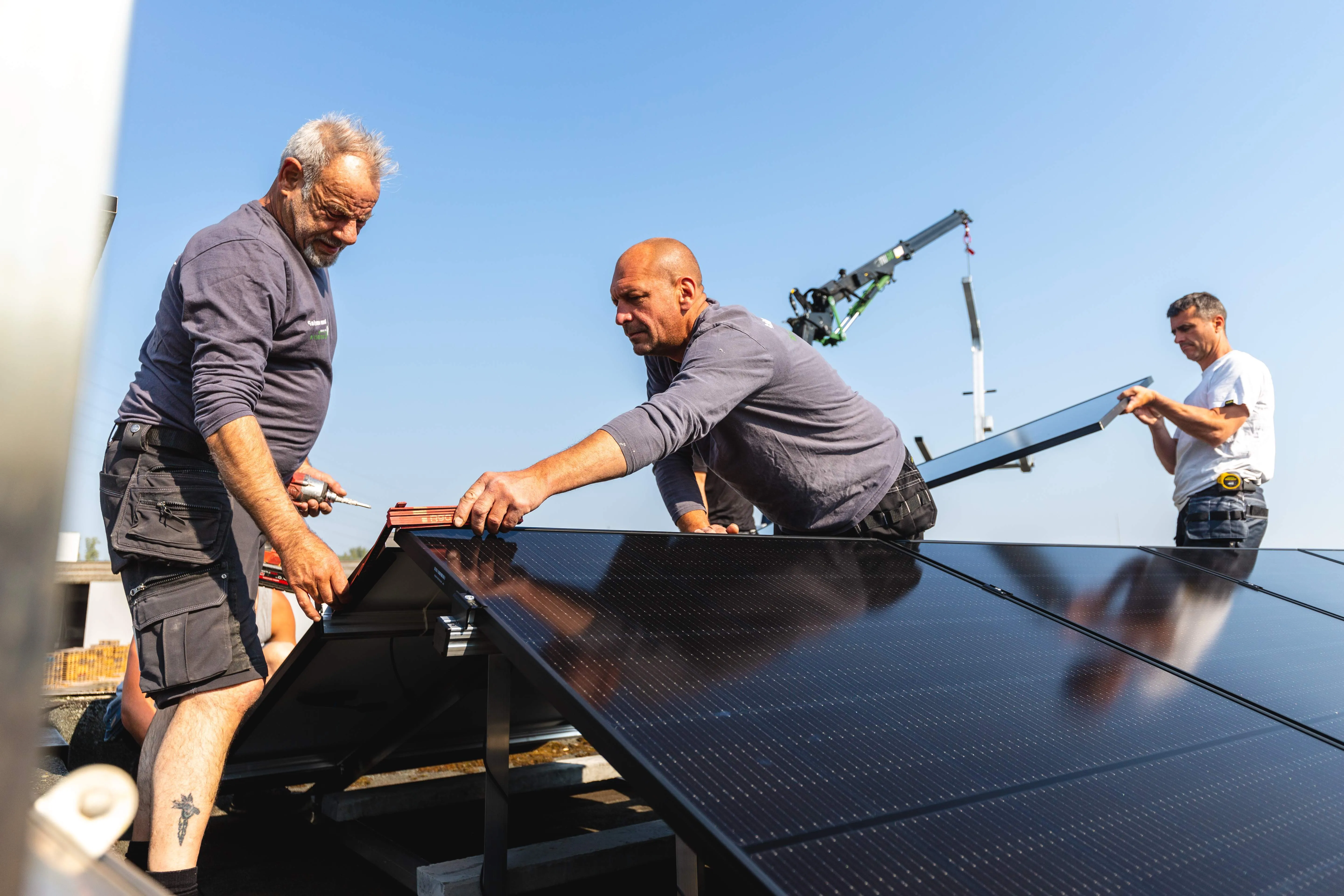 Two men working on a solar panel on top of a building.