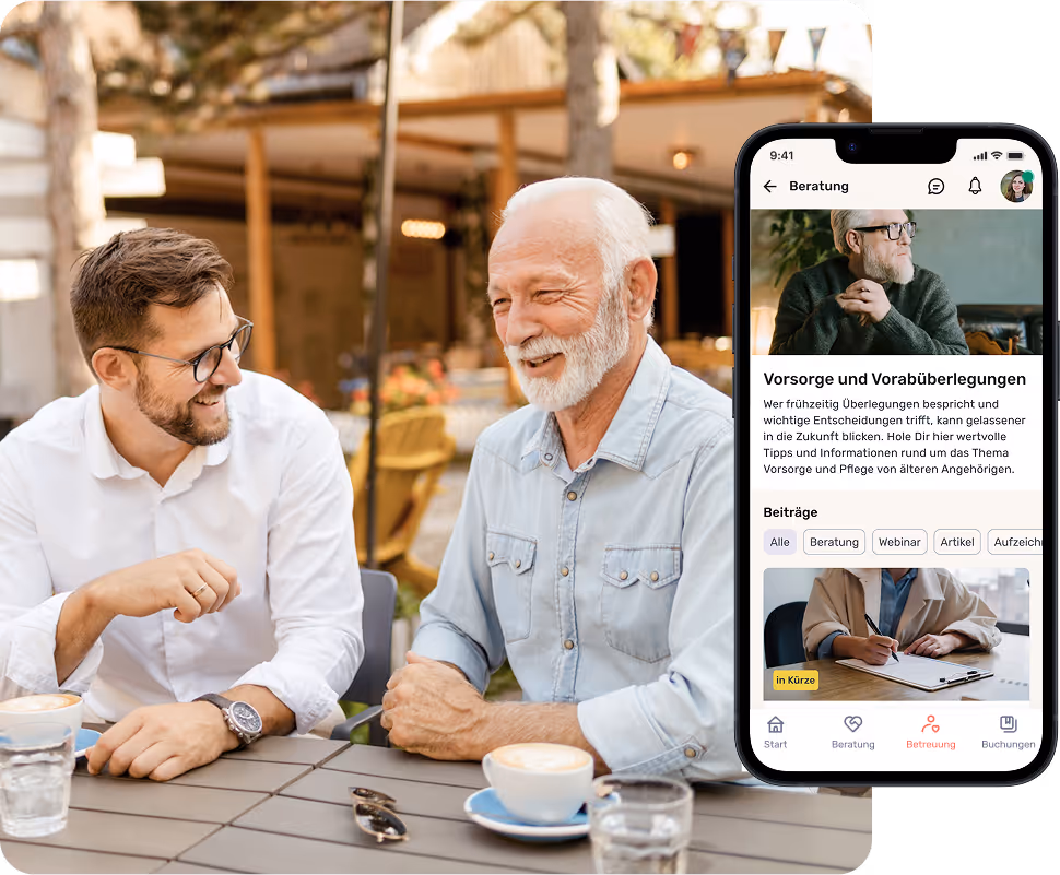 Ein älterer Mann und ein jüngerer Mann unterhalten sich lächelnd bei Kaffee im Freien. Daneben ist die heycare-App auf einem Smartphone zu sehen.