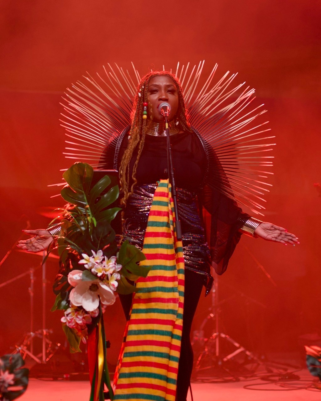 Rochelle Bradshaw wearing Rastafarian colors and performing live reggae music with dramatic red lighting at Railyard Live concert venue in Rogers, Arkansas.
