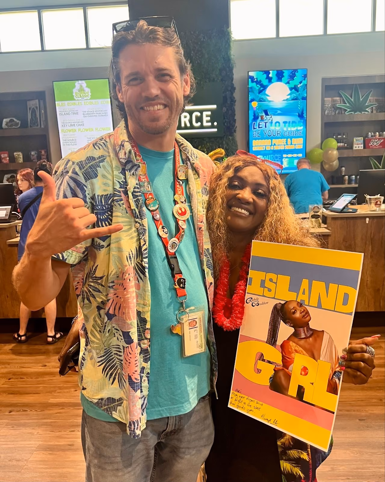 Christian and Rochelle Bradshaw holding Island Girl album artwork inside The Source dispensary during 6th anniversary celebration.