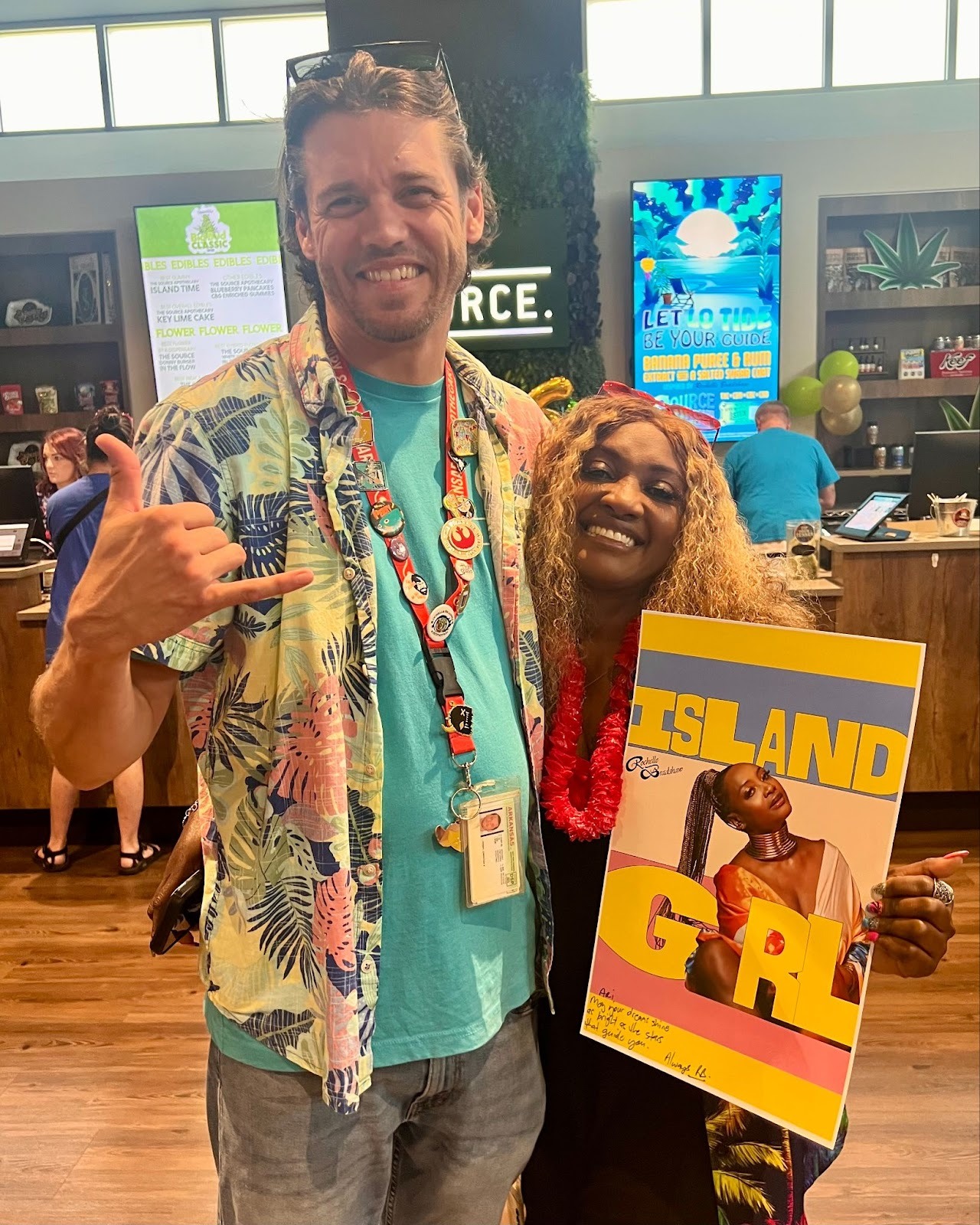 Christian and Rochelle Bradshaw holding Island Girl album artwork inside The Source dispensary during 6th anniversary celebration.
