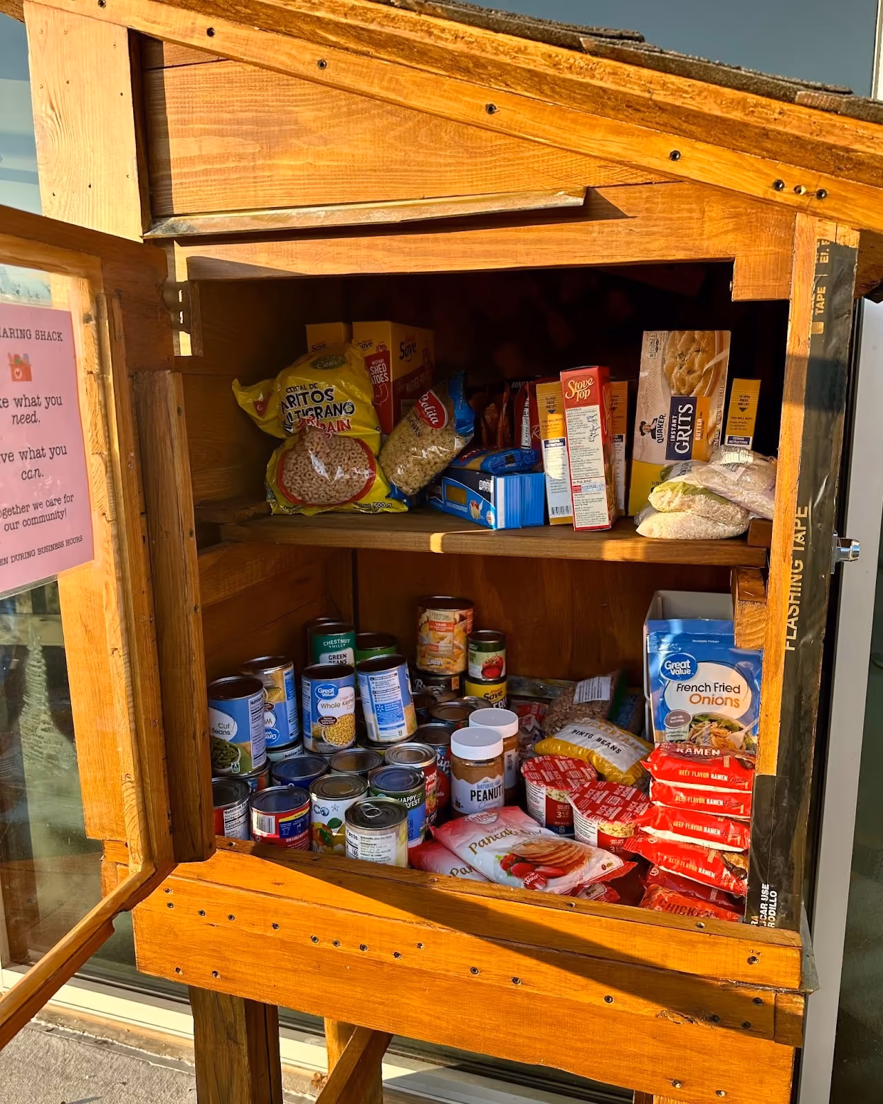The Source Sharing Shack community pantry filled with donated canned goods and food items.
