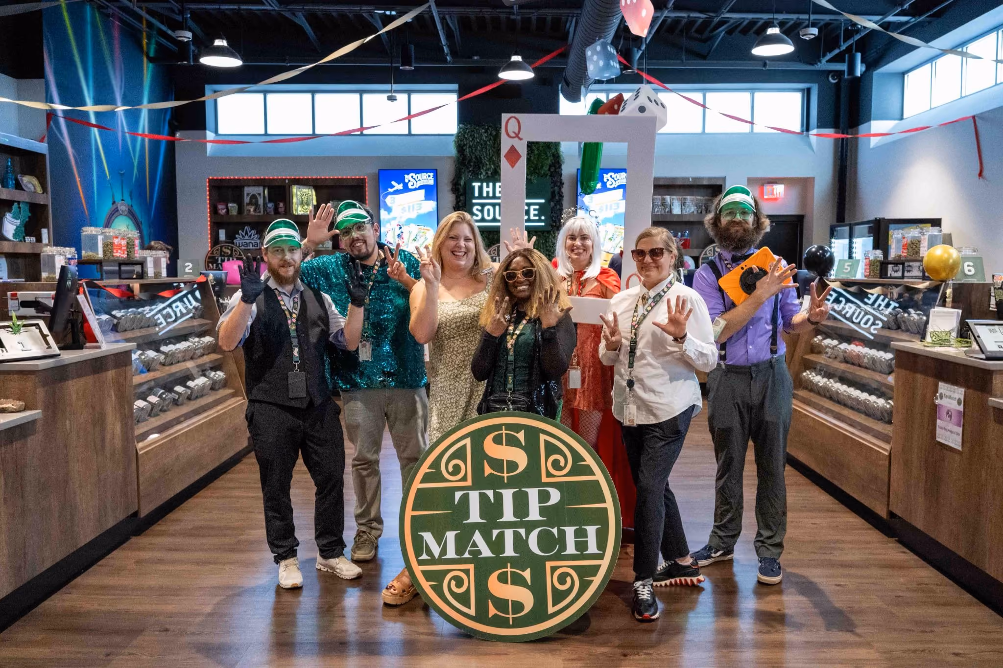 The Source staff celebrate their Lucky 7 Anniversary weekend, gathered around the Tip Match sign benefiting the Northwest Arkansas Women's Shelter.