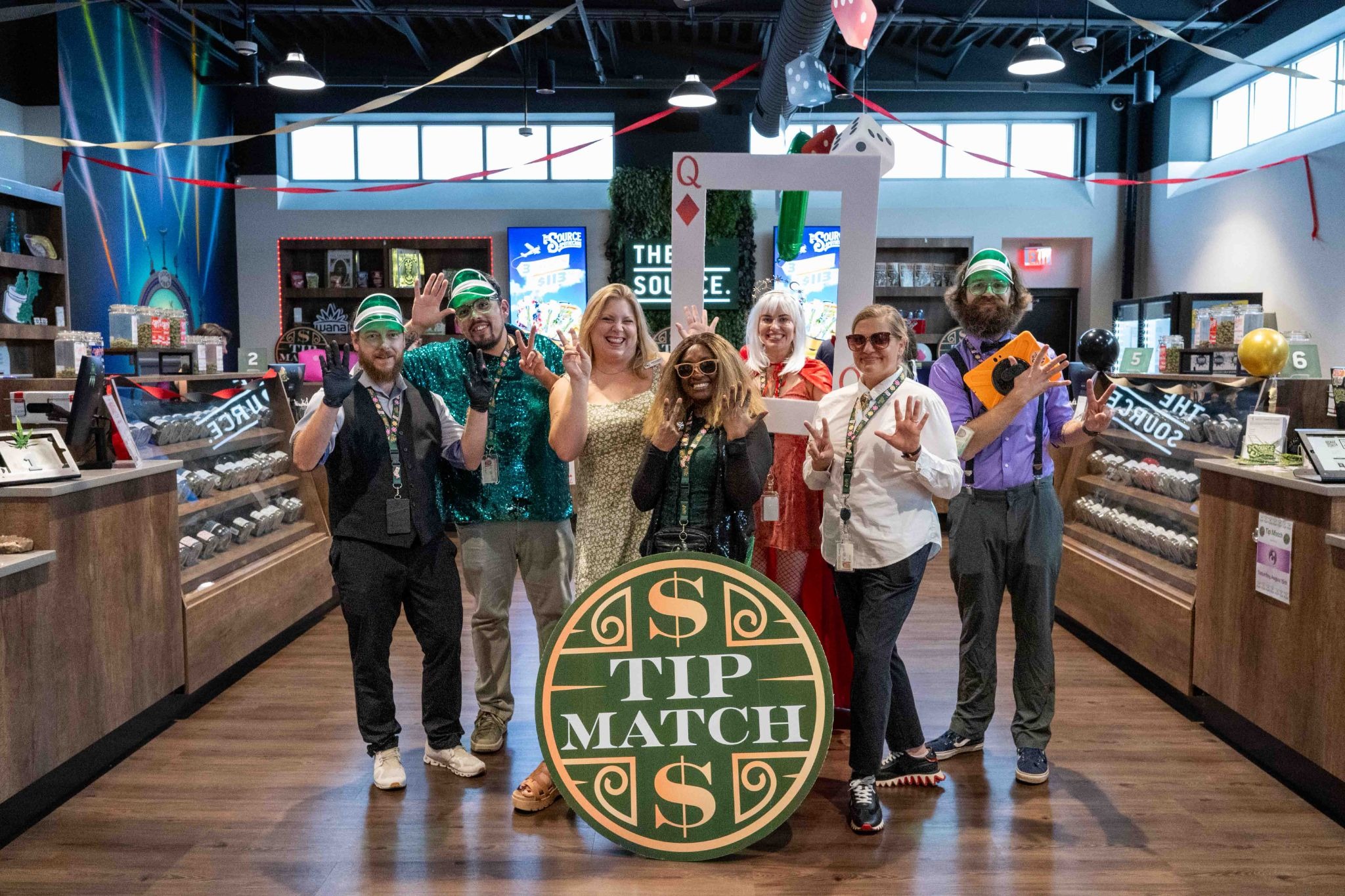 The Source staff celebrate their Lucky 7 Anniversary weekend, gathered around the Tip Match sign benefiting the Northwest Arkansas Women's Shelter.