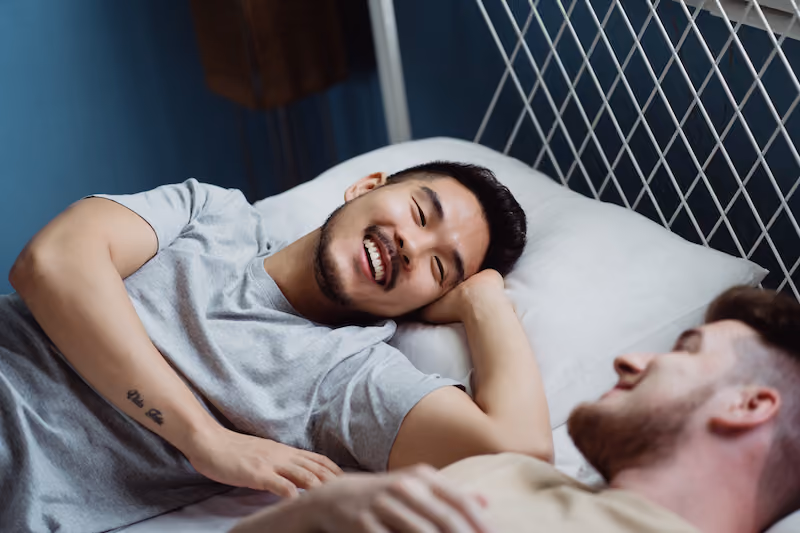 ベッドで微笑むあうふたりの男性