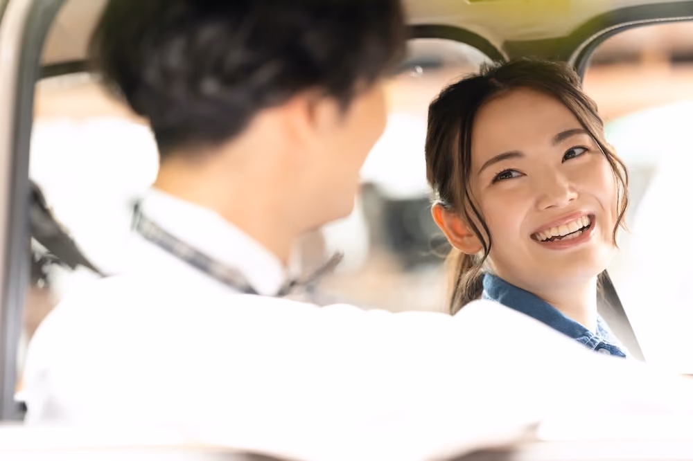 車の中で楽しそうに男性とおしゃべりをする女性