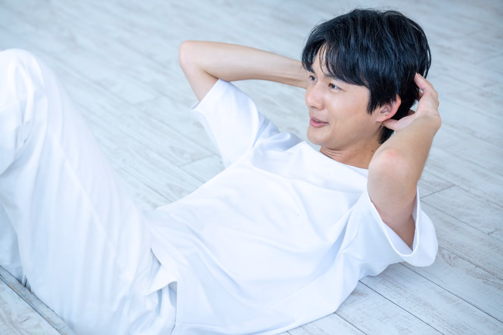 床に仰向けになり膝を立て腹筋を鍛える男性