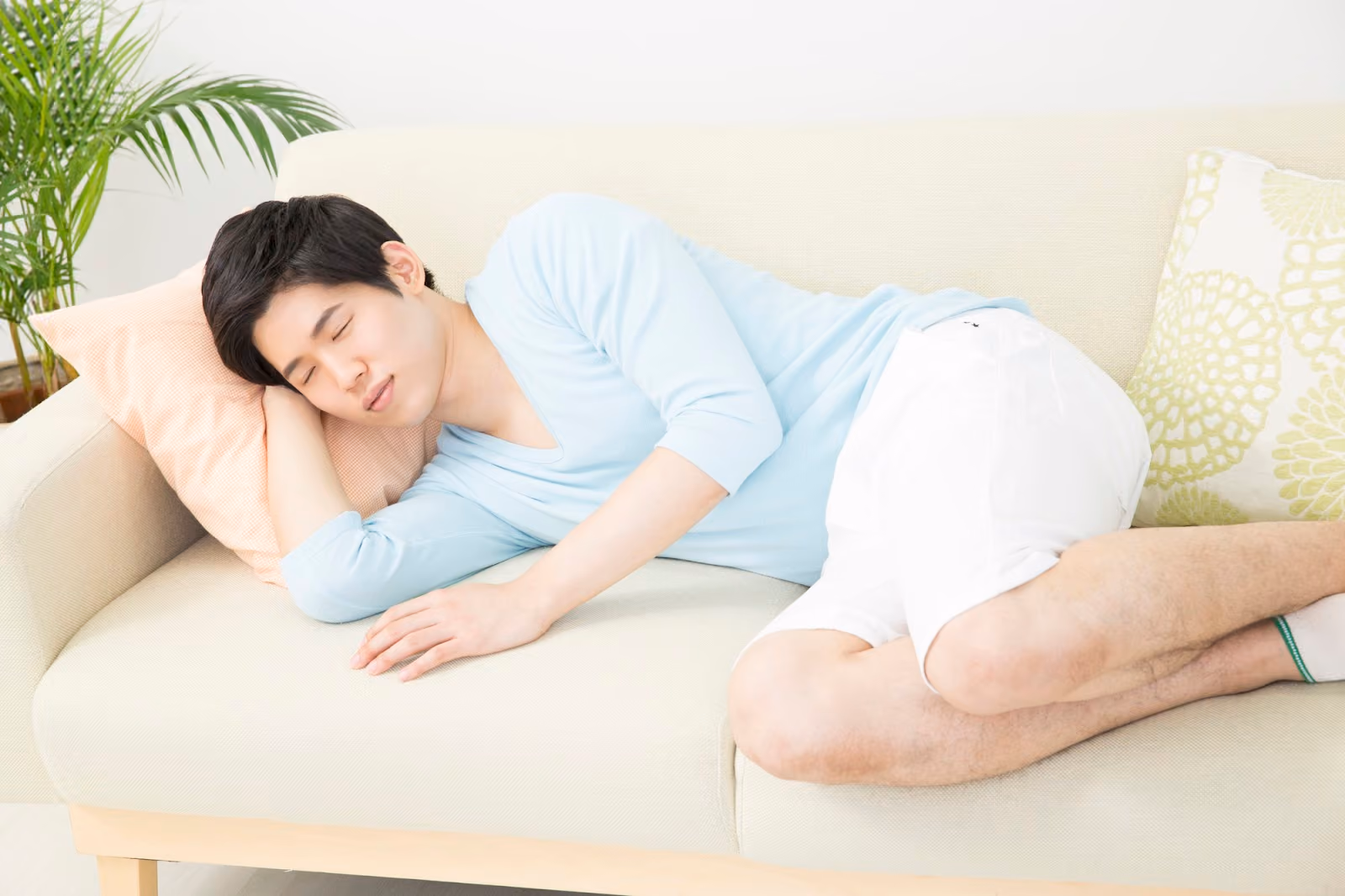 白いソファで横向きに寝る男性