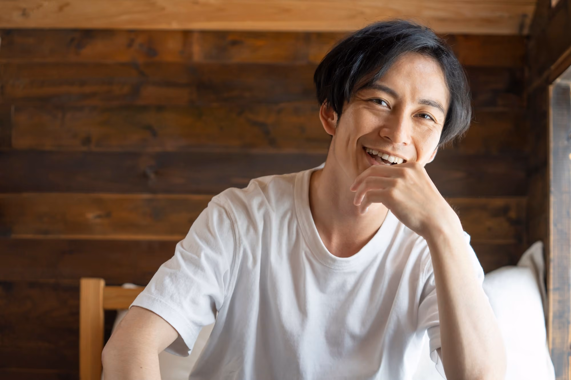 木造の小屋の中で満面の笑みを浮かべる若い男性