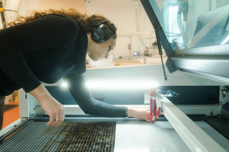 A woman working with a laser cutter