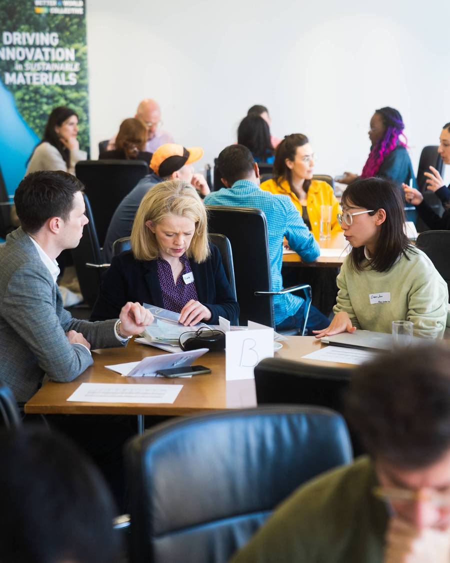 3 people sat around table discussing together whilst one person looks through paperwork 