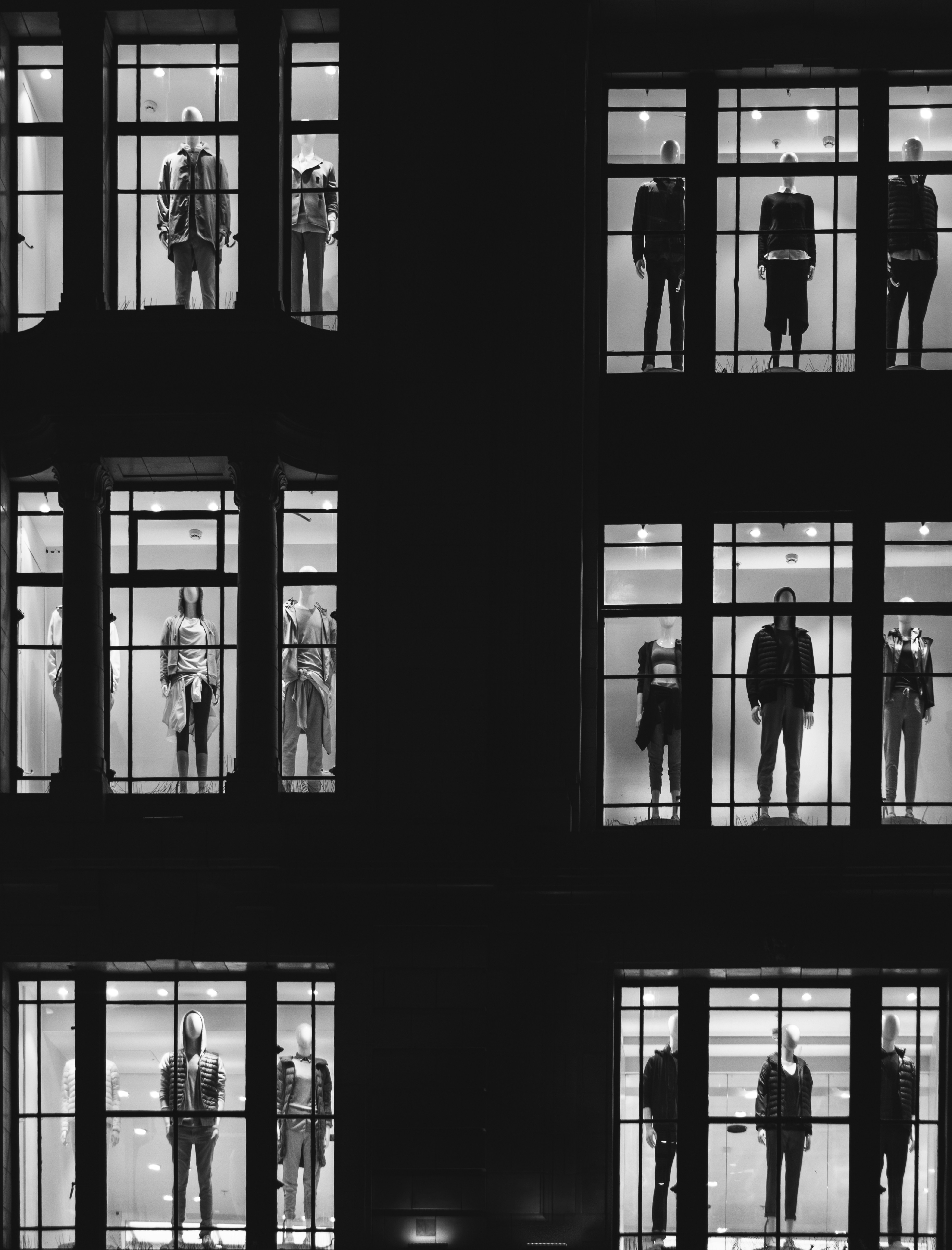A stylised photo of mannequins in multiple windows in a department store.