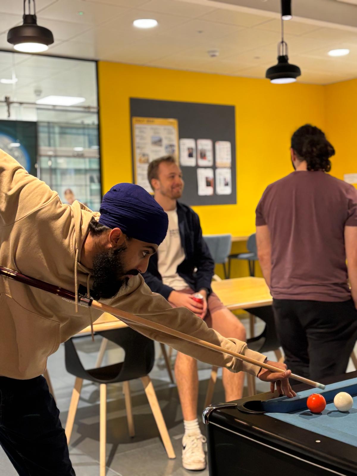 Plus X Innovation member playing a game of pool during the weekly social .