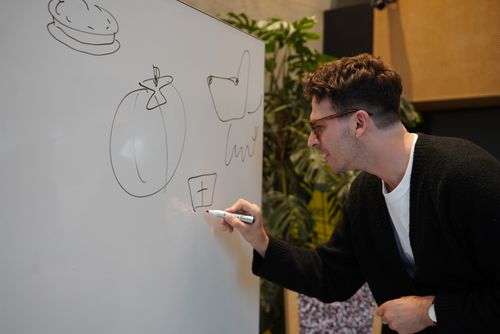 A Plus X Innovation Team member drawing out something on a white board .