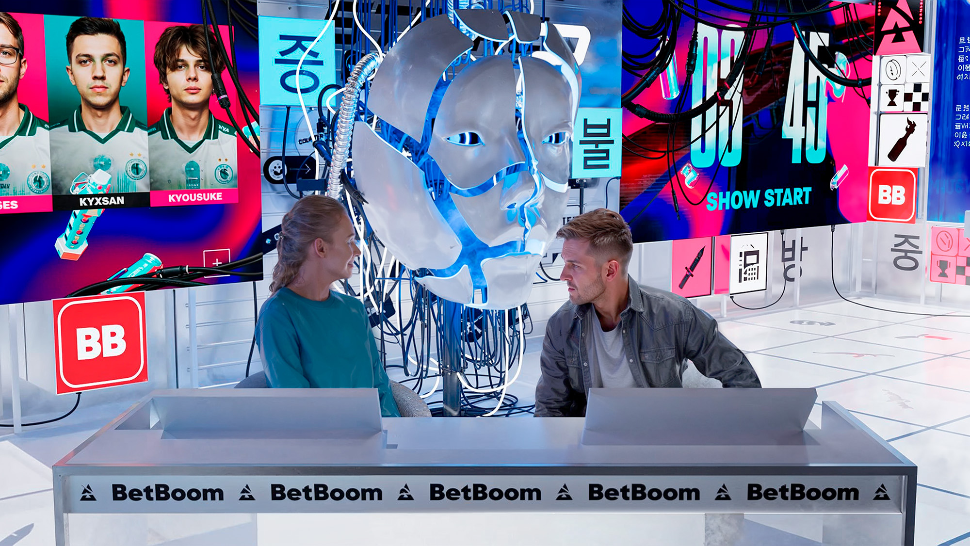 BLAST Studio hosts at the broadcast desk with the central kinetic sculpture