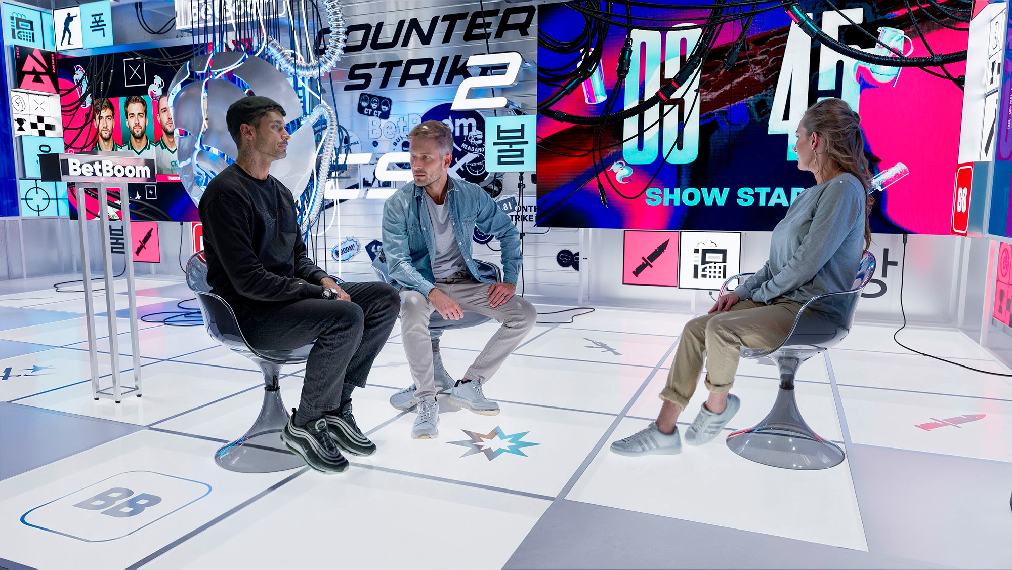 Three presenters inside the BLAST Studio broadcast set